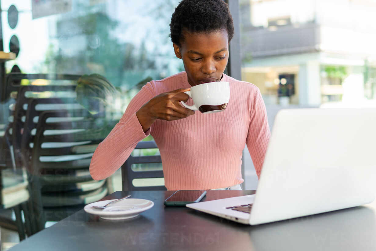 https://us.images.westend61.de/0001988579pw/an-african-woman-is-focused-on-her-laptop-screen-while-sipping-coffee-at-a-cafe-reflecting-productivity-and-a-casual-work-environment-ADSF56624.jpg